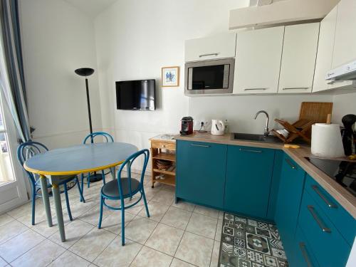 cocina con armarios azules, mesa y sillas en Appartement en duplex avec balcon, 5 minutes plage et centre village, en La Couarde-sur-Mer