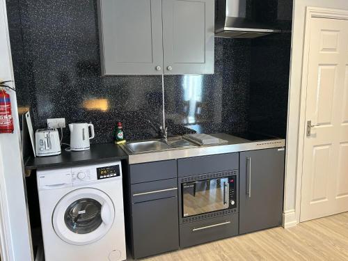 a kitchen with a sink and a washing machine at Southernwood - Family Studio in Didcot