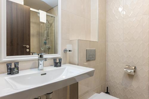 a white bathroom with a sink and a mirror at Gradiali Wellness and SPA in Palanga