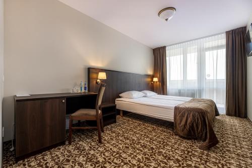 a hotel room with a bed and a desk and a window at Gradiali Wellness and SPA in Palanga