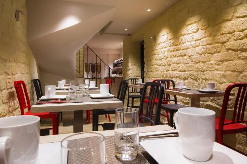 un restaurant avec des tables et des chaises et un mur de pierre dans l'établissement Best Western Quartier Latin Pantheon, à Paris