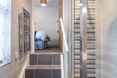 a bathroom with a walk in shower next to a staircase at Oakdene in Deganwy