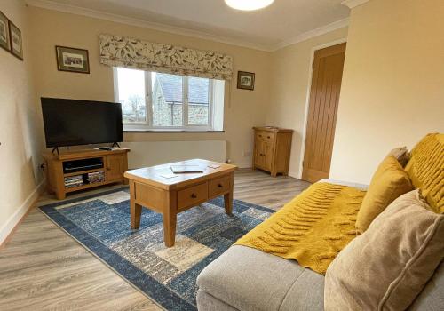 a living room with a couch and a flat screen tv at Maesyfelin Isaf Apartment in Llanybydder