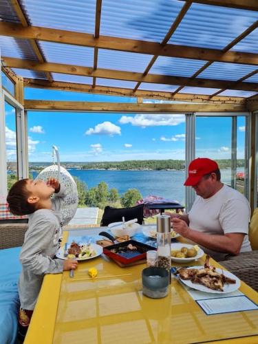 a man and a child sitting at a table with food at Archipelago villa, cabin & sauna jacuzzi with sea view, 30 minutes from Stockholm in Tyresö