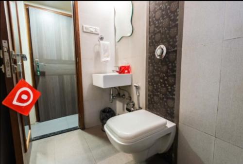 La petite salle de bains est pourvue de toilettes et d'un lavabo. dans l'établissement Apollo Guest House, à Mumbai