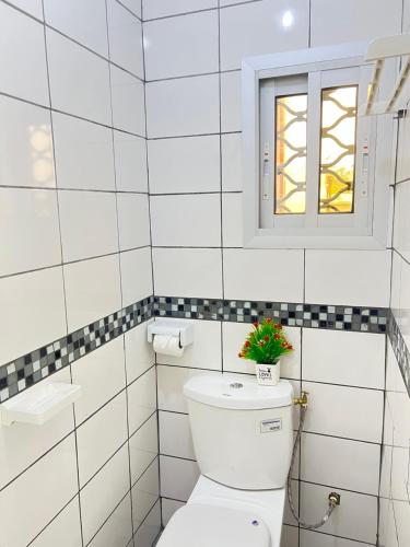 a white bathroom with a toilet and a window at Chambre moderne avec cuisine à Bonamoussadi (Kotto) in Douala