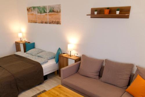 een kleine kamer met een bed en een bank bij Panoráma Apartman in Veszprém