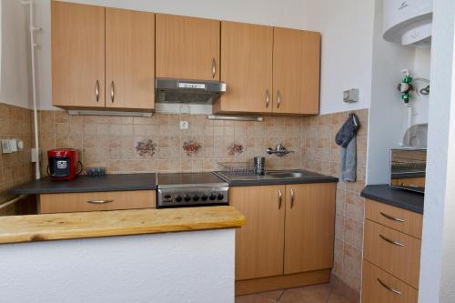 a kitchen with wooden cabinets and a stove top oven at Panoráma Apartman in Veszprém