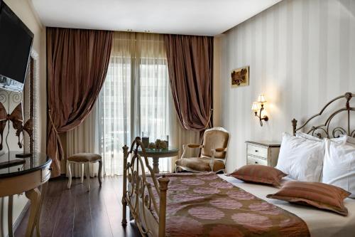 sypialnia z łóżkiem, krzesłem i oknem w obiekcie Danai Hotel & Spa w mieście Olympiakí Aktí