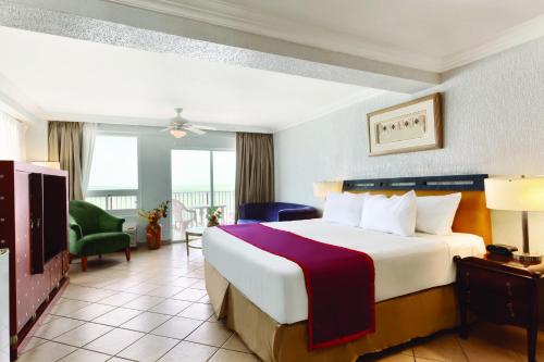 um quarto de hotel com uma cama grande e uma janela grande em Ramada by Wyndham Princess Belize City em Cidade de Belize