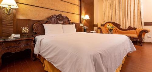 a bedroom with a large white bed with a wooden headboard at Chicago Motel in Jiaoxi