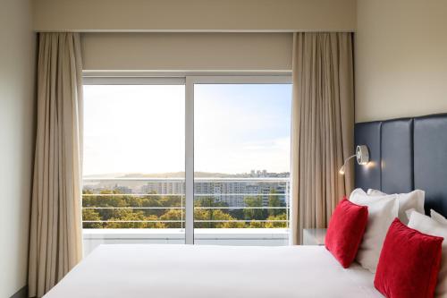 a bedroom with a large bed with a large window at Melia Setubal in Setúbal