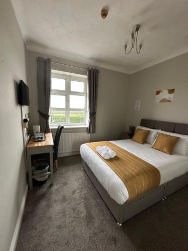 a bedroom with a bed and a desk and a window at Rettendon Lodge in Battlesbridge