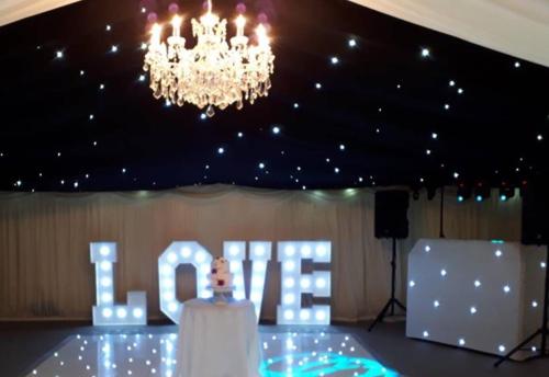 a stage with a chandelier and a sign that says love at Rettendon Lodge in Battlesbridge
