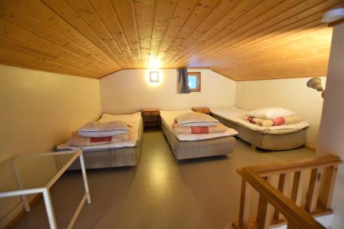 a room with three beds in it with a wooden ceiling at Pyhtään Vuokramökit in Tuuski
