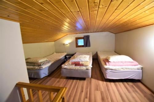 two beds in a room with a wooden ceiling at Pyhtään Vuokramökit in Tuuski