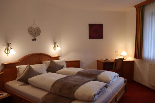 een slaapkamer met een bed, een tafel en een raam bij Apart Andrea in Holzgau