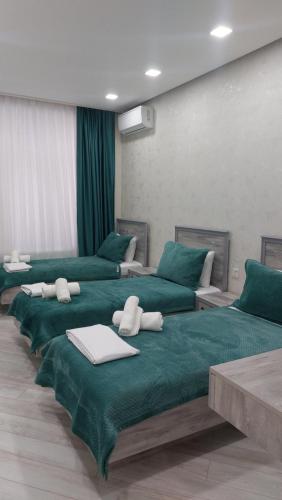 um quarto com quatro camas com lençóis e mesas verdes em Villa Star em Gabala