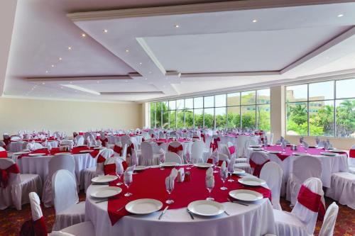 a room filled with tables and chairs with red and white tablecloths at Ramada by Wyndham Princess Belize City in Belize City