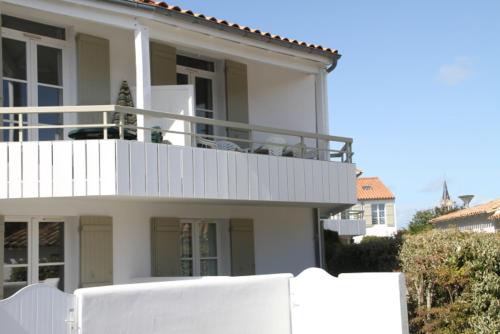 une maison blanche avec une clôture blanche devant elle dans l'établissement Appartement en duplex avec balcon, 5 minutes plage et centre village, à La Couarde-sur-Mer