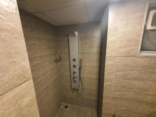 een douche in een badkamer met een tegelwand bij WEEKEND ADDRESS by Guest Pals in Surat