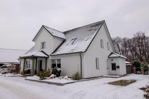 ein weißes Haus mit einem Dach im Schnee in der Unterkunft Ferienwohnung Heinrich in Kröslin