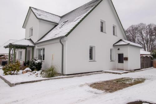 ein weißes Haus mit Schnee auf dem Boden in der Unterkunft Ferienwohnung Heinrich in Kröslin