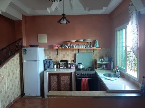 a kitchen with a white refrigerator and a sink at Duplex Riad Sidi Bouzid in El Jadida