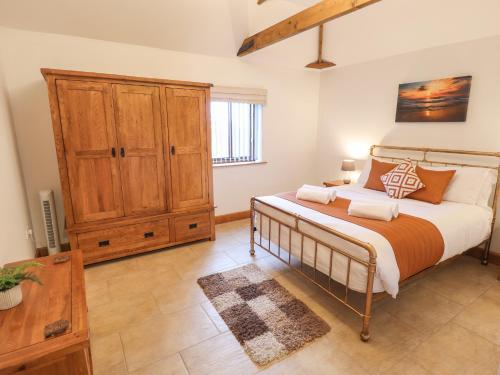 a bedroom with a bed and a wooden cabinet at Tawny Cottage in Alford