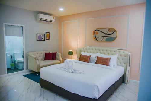 1 dormitorio con 1 cama blanca grande y 1 silla en JB Grand Resort, en Nakhon Si Thammarat