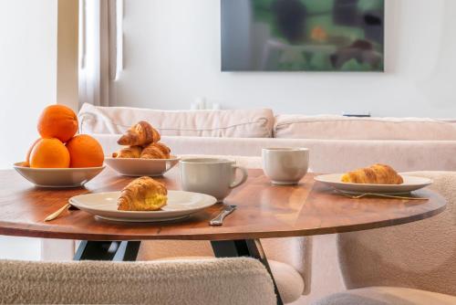 a table with plates of croissants and oranges on it at Moderno Apartamento in Marbella