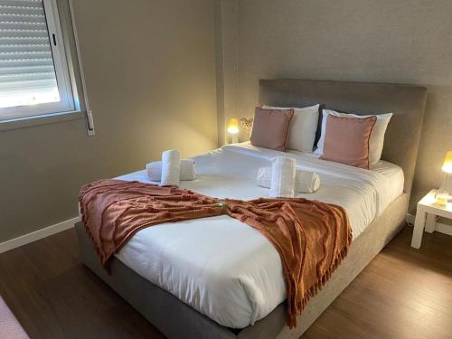 a bedroom with a large bed with white sheets and pink pillows at A Casa do Chapéu de Palha in Setúbal