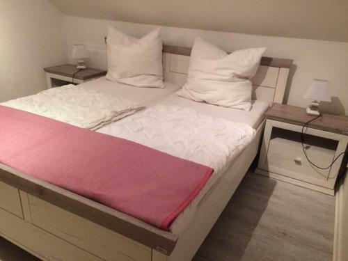 Una cama con sábanas blancas y una manta roja. en Ferienwohnung Möwennest en Timmendorfer Strand