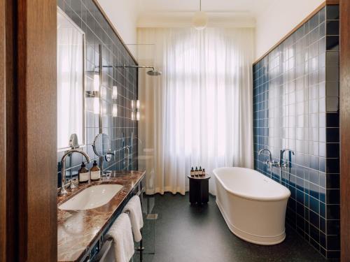 a bathroom with two sinks and a bath tub at Boutique Hotel Château Royal in Berlin