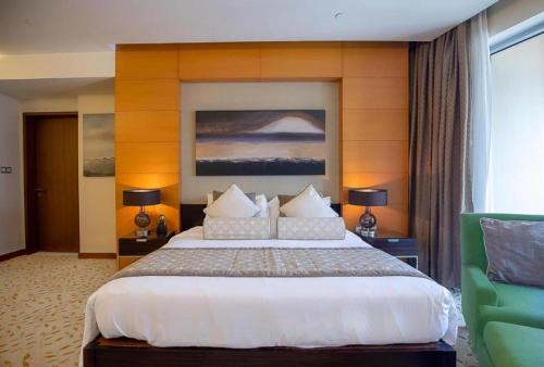 um quarto com uma cama grande e uma cadeira verde em OSTAY -Address Dubai Mall - The Residence em Dubai