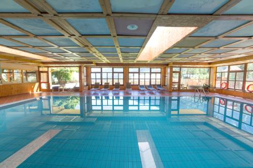 duży kryty basen z niebieskimi podłogami i oknami w obiekcie Hotel Sancamillo w mieście Dimaro