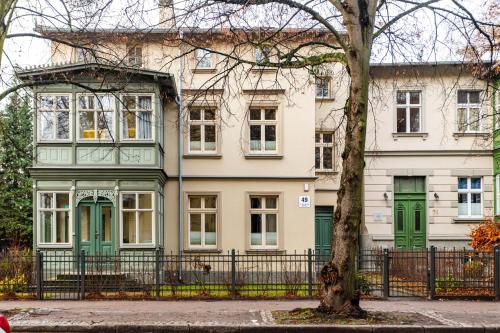 a large white house with green doors and a tree at Victus Apartamenty, Villa Haffnera in Sopot