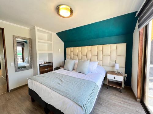 a bedroom with a large bed with a blue wall at Spazios Apart Hotel Reñaca in Viña del Mar
