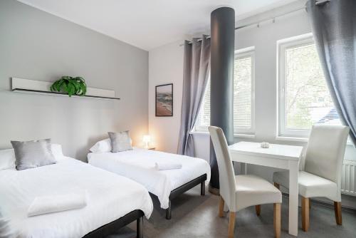 - une chambre avec deux lits, une table et une chaise dans l'établissement Keja Aparts - 04 Gdynia Centrum, à Gdynia