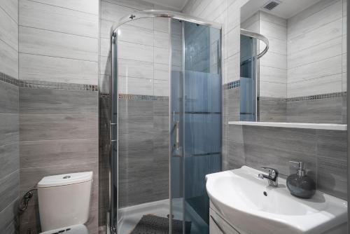 La salle de bains est pourvue de toilettes, d'un lavabo et d'une douche. dans l'établissement Keja Aparts - 04 Gdynia Centrum, à Gdynia