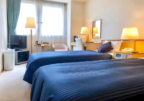 a hotel room with two beds and a television at HOTEL LiVEMAX Sapporo Ekimae in Sapporo