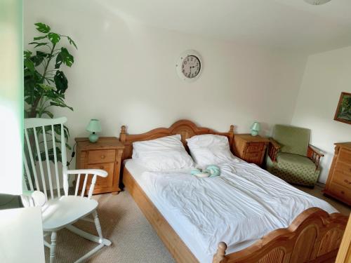 a bedroom with a bed and a chair and a clock at Landhaus mit Pool, Bungalow in der Natur in Hohenbollentin