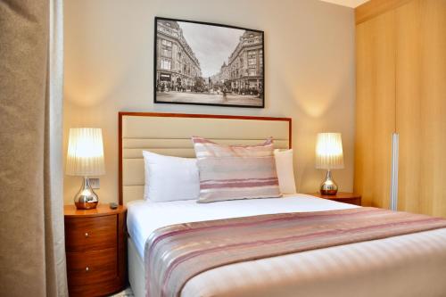 a bedroom with a large bed with two lamps at Sanctum Belsize Road in London