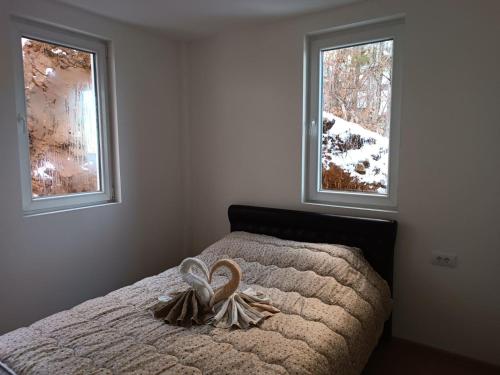 a bedroom with a bed with two windows at Apartmani Moskva in Kopaonik