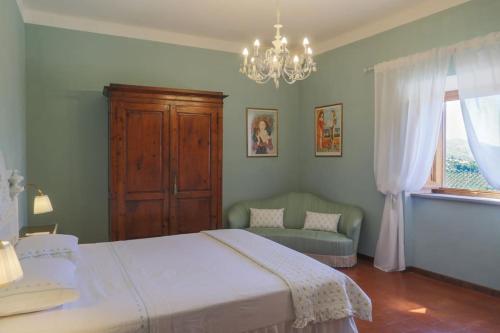 una camera con letto, sedia e lampadario a braccio di Villa il Balocco a Gaiole in Chianti