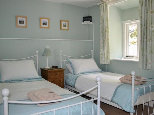 1 dormitorio con 2 camas y ventana en Bluebell Cottage, en Coniston