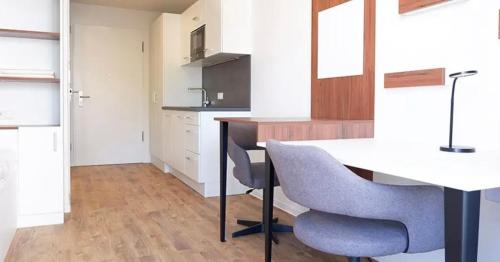 een keuken met een witte tafel en 2 stoelen bij Gehobenes Apartment mit Balkon in Reutlingen