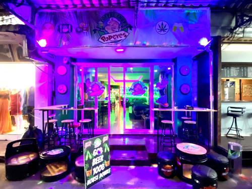 a bar with purple lights and stools in a room at Popeyes Hostel, Coffeeshop & Beer Bar in Patong Beach