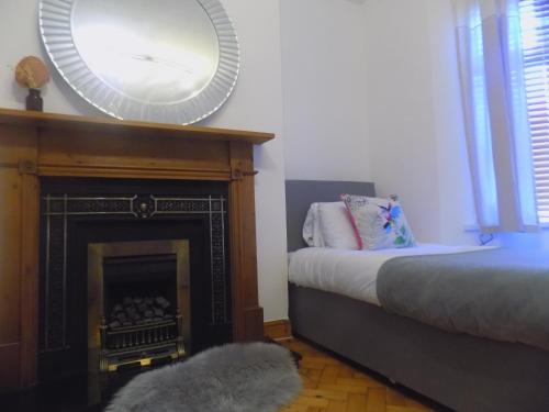 Schlafzimmer mit einem Kamin, einem Spiegel und einem Bett in der Unterkunft Rhiwbina House in Cardiff