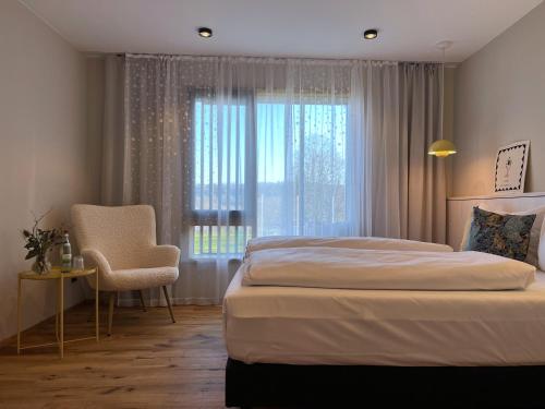 Hotel-Weingut Bernard في Sulzfeld am Main: غرفة نوم بسرير وكرسي ونافذة